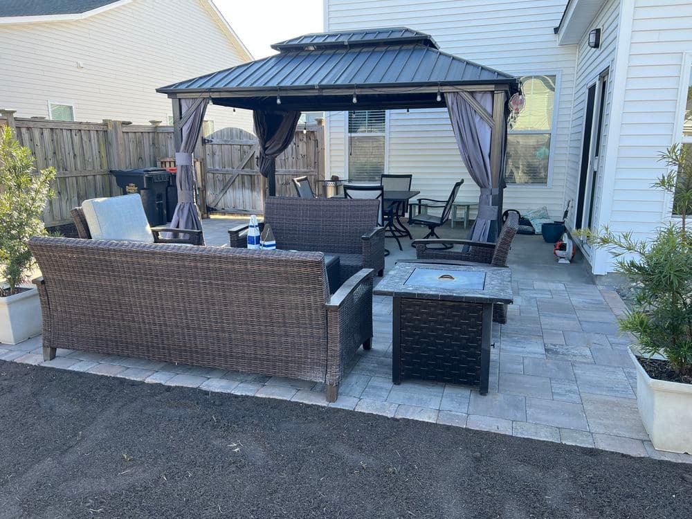 Outdoor patio with a gazebo, wicker furniture, and a stone paver floor for relaxation.